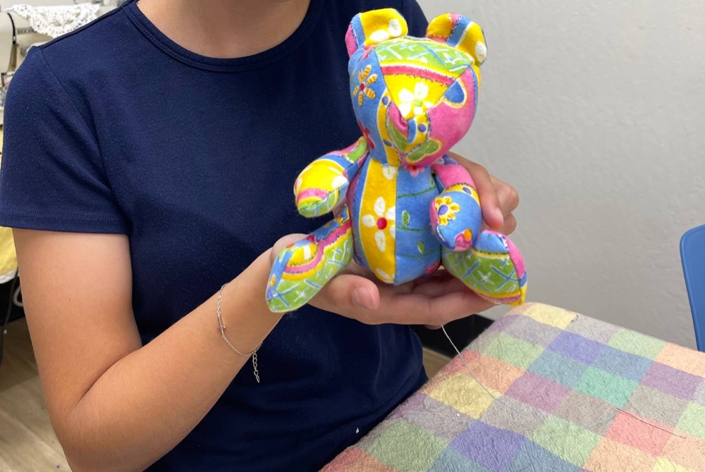 Student holding a colorful patchwork teddy bear