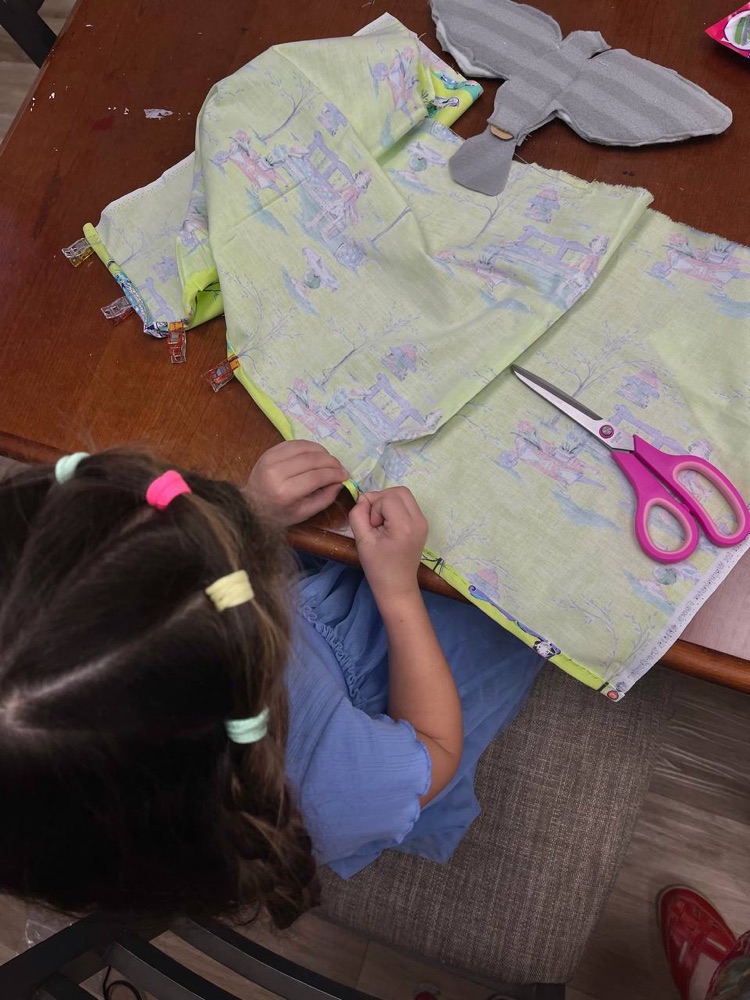 Student hand-sewing a soft toy from patterned fabric